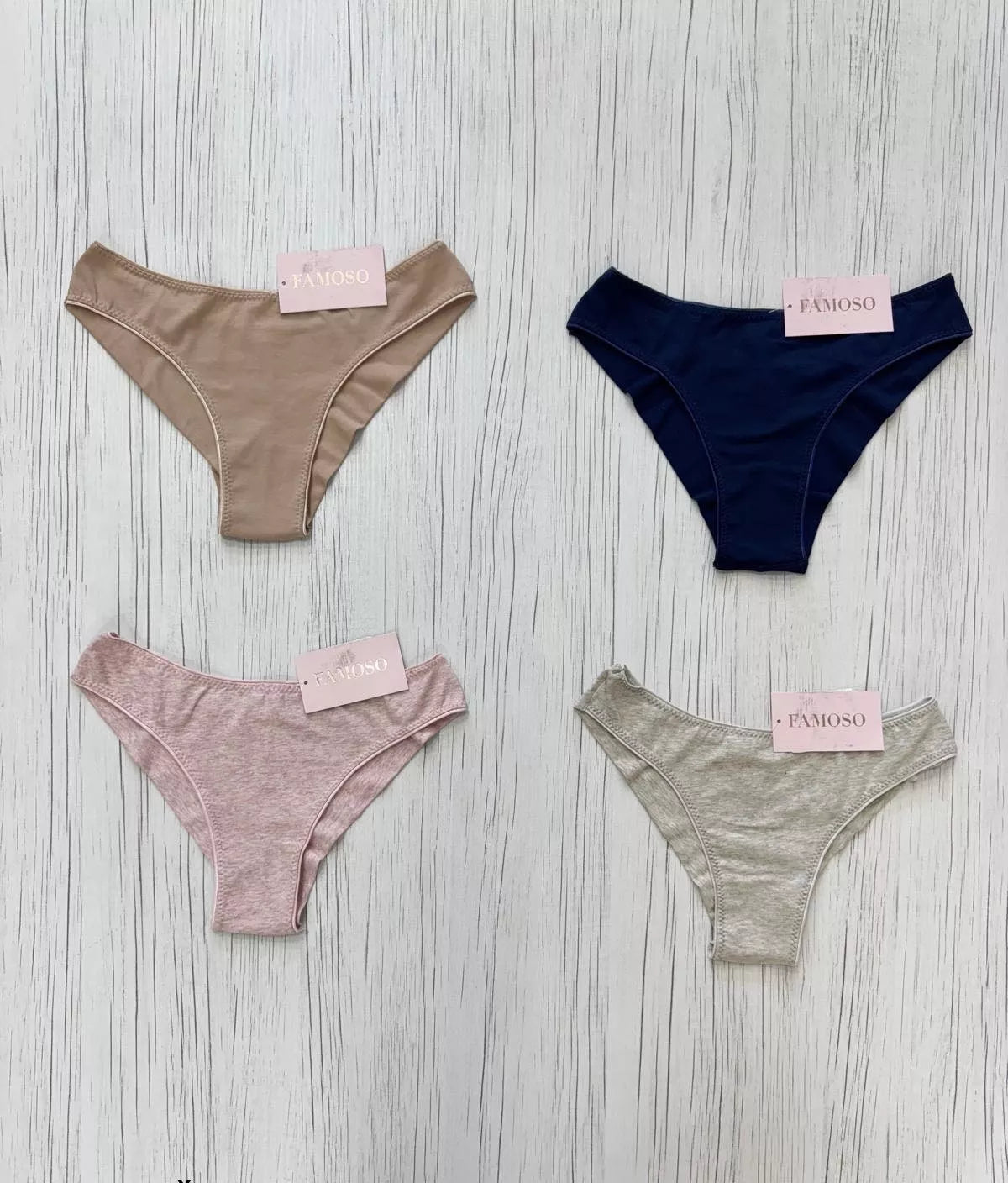 Four pairs of underwear in different colors with 'Famous' tags on a wooden surface.