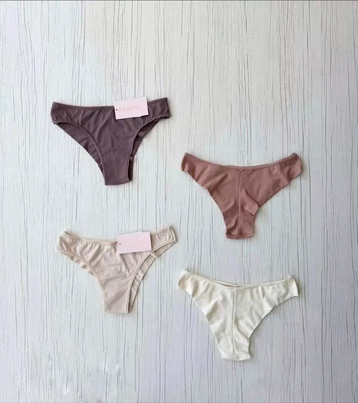 Four pairs of underwear in different colors on a light wooden surface.