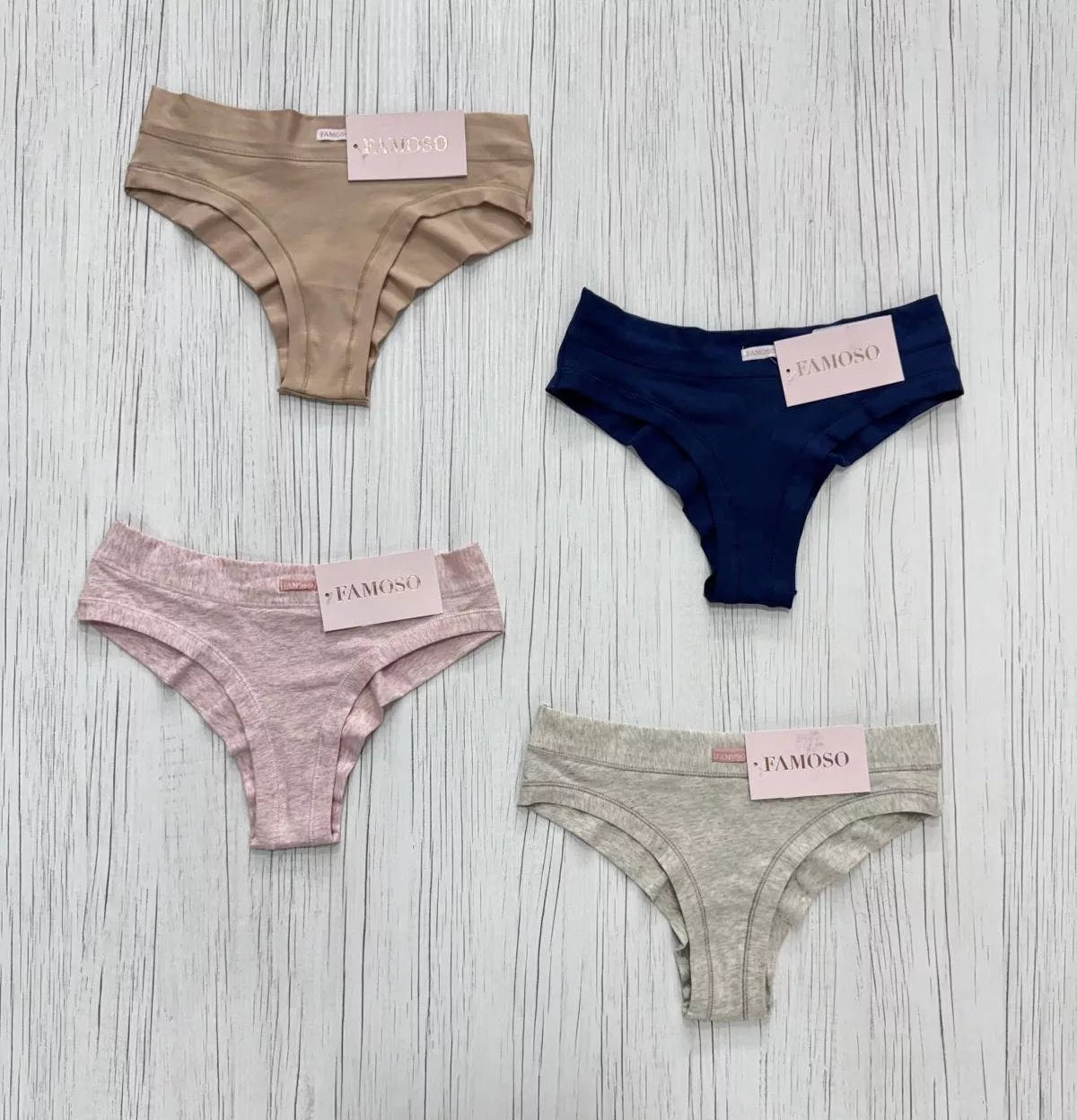 Four pairs of underwear in different colors with 'Famoso' labels on a wooden surface.