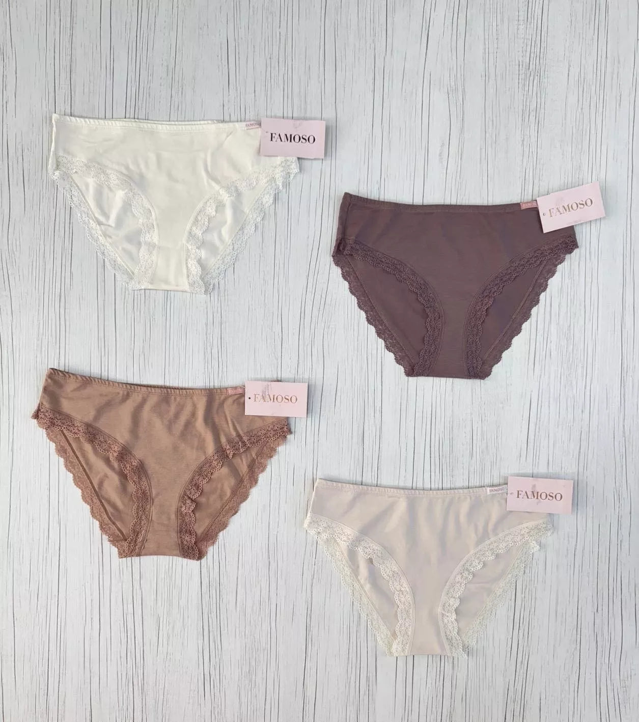 Four pairs of lace-trimmed underwear from Famoso on a wooden surface.