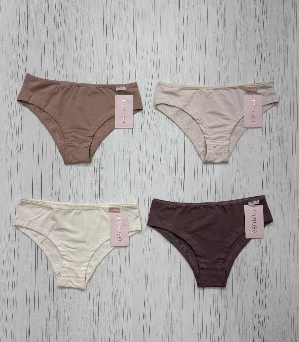 Four pairs of underwear in different colors on a textured surface