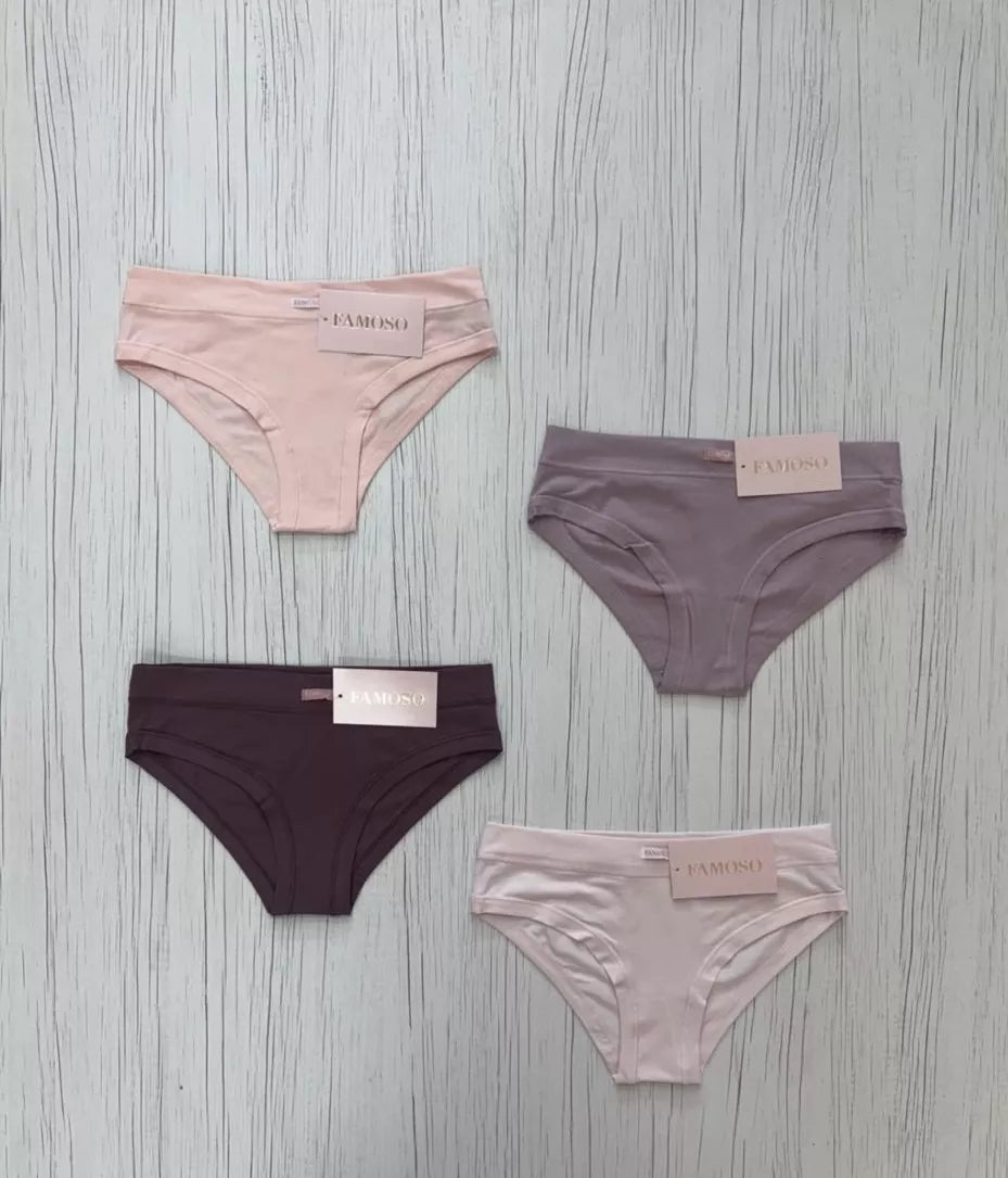 Four pairs of underwear in pink, brown, and black on a gray wooden surface.