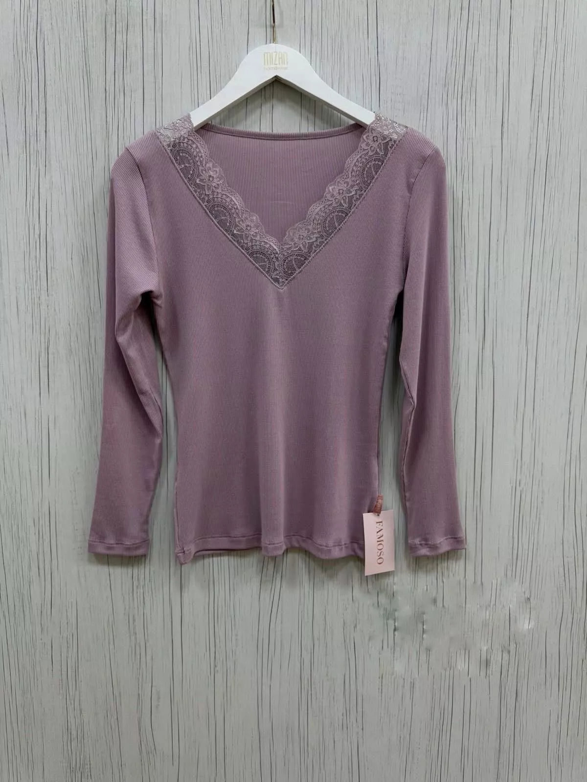 Purple long-sleeve top with lace neckline on a hanger against a wooden background