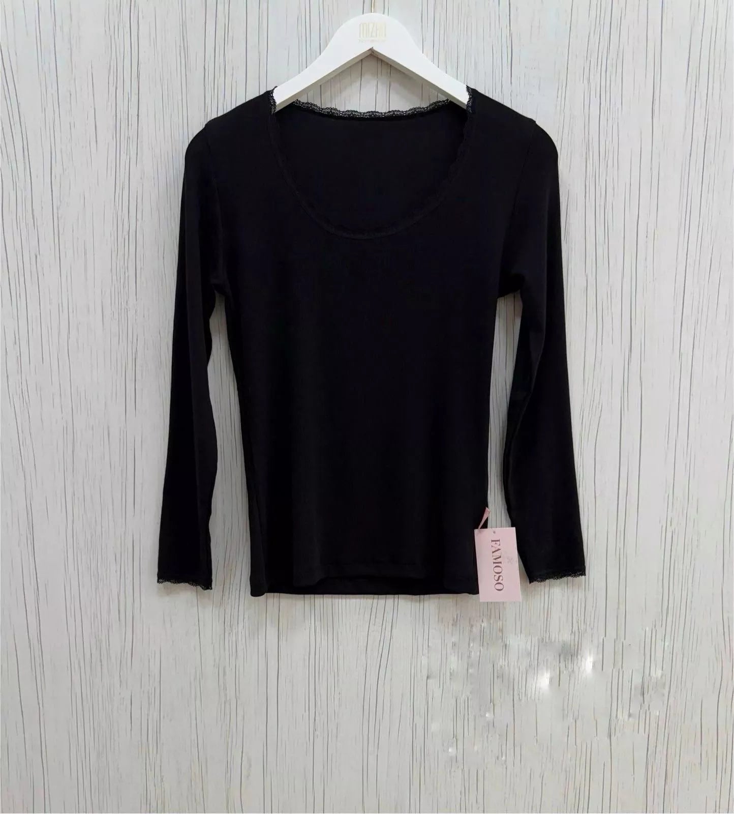 Black long-sleeve shirt on a hanger with a visible brand tag against a light wooden background