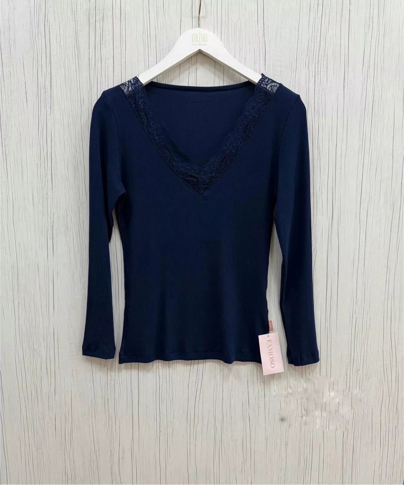 Navy blue long-sleeve top with lace details on a white hanger against a light wooden background.