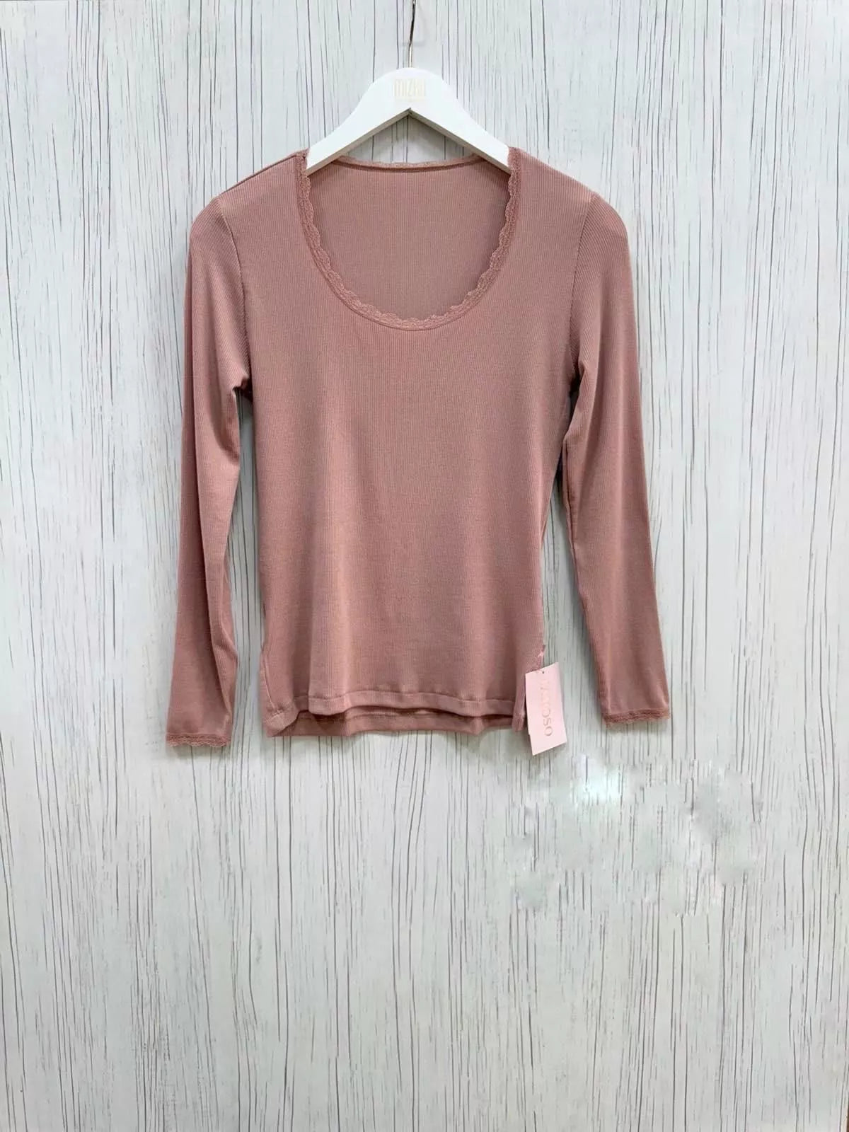 Pink long-sleeve shirt on a hanger against a wooden background