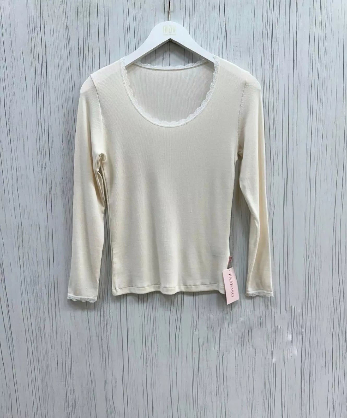 Beige long-sleeve shirt on a hanger against a gray wooden background