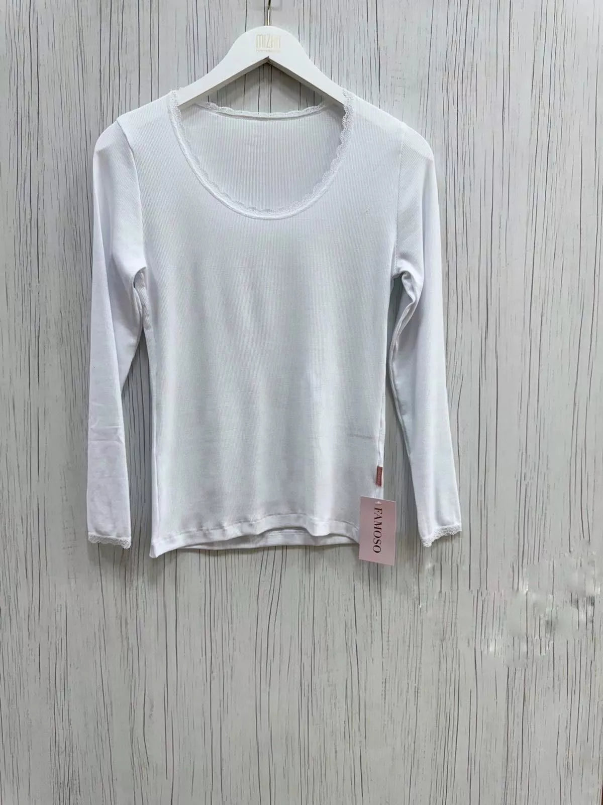 White long-sleeve shirt on a hanger with a visible tag against a wooden background